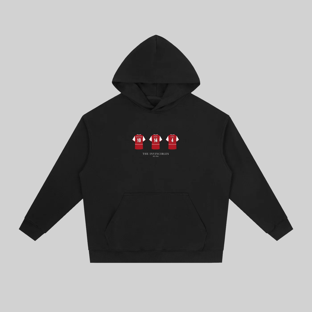 A black pullover hoodie with a front kangaroo pocket and a small chest graphic showing three red soccer jerseys with white numbers. The hoodie is displayed flat against a solid gray background.
