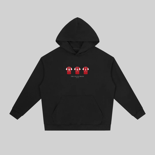A black pullover hoodie with a front kangaroo pocket and a small chest graphic showing three red soccer jerseys with white numbers. The hoodie is displayed flat against a solid gray background.