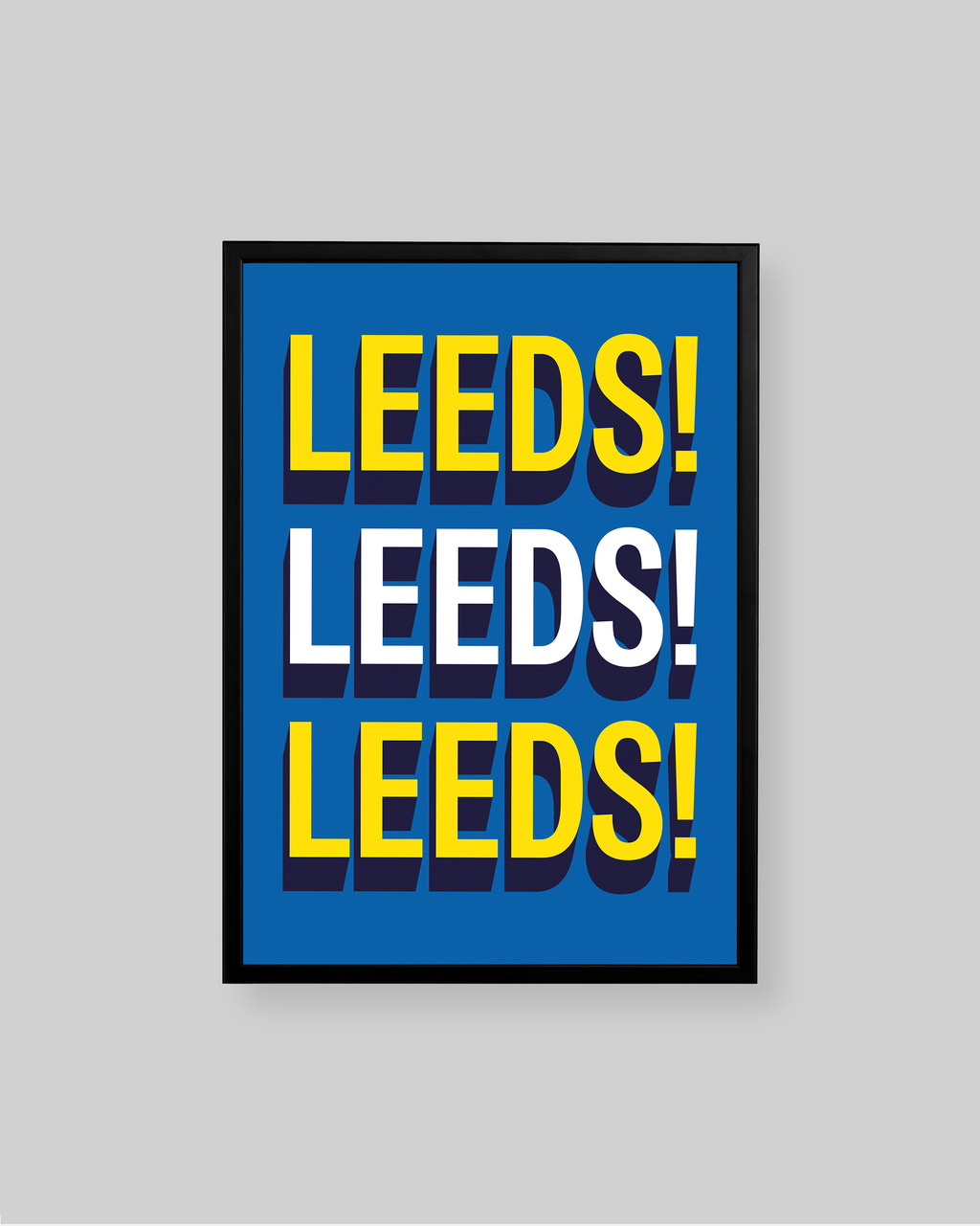 A framed typographic wall art print featuring the word 'LEEDS!' repeated three times in bold yellow and white letters on a bright blue background, shown against a light gray wall.