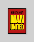 A framed poster with a bold red background and large yellow text reading 'MAN UNITED' with smaller black text above reading 'GLORY, GLORY'. The poster is shown against a light gray background.