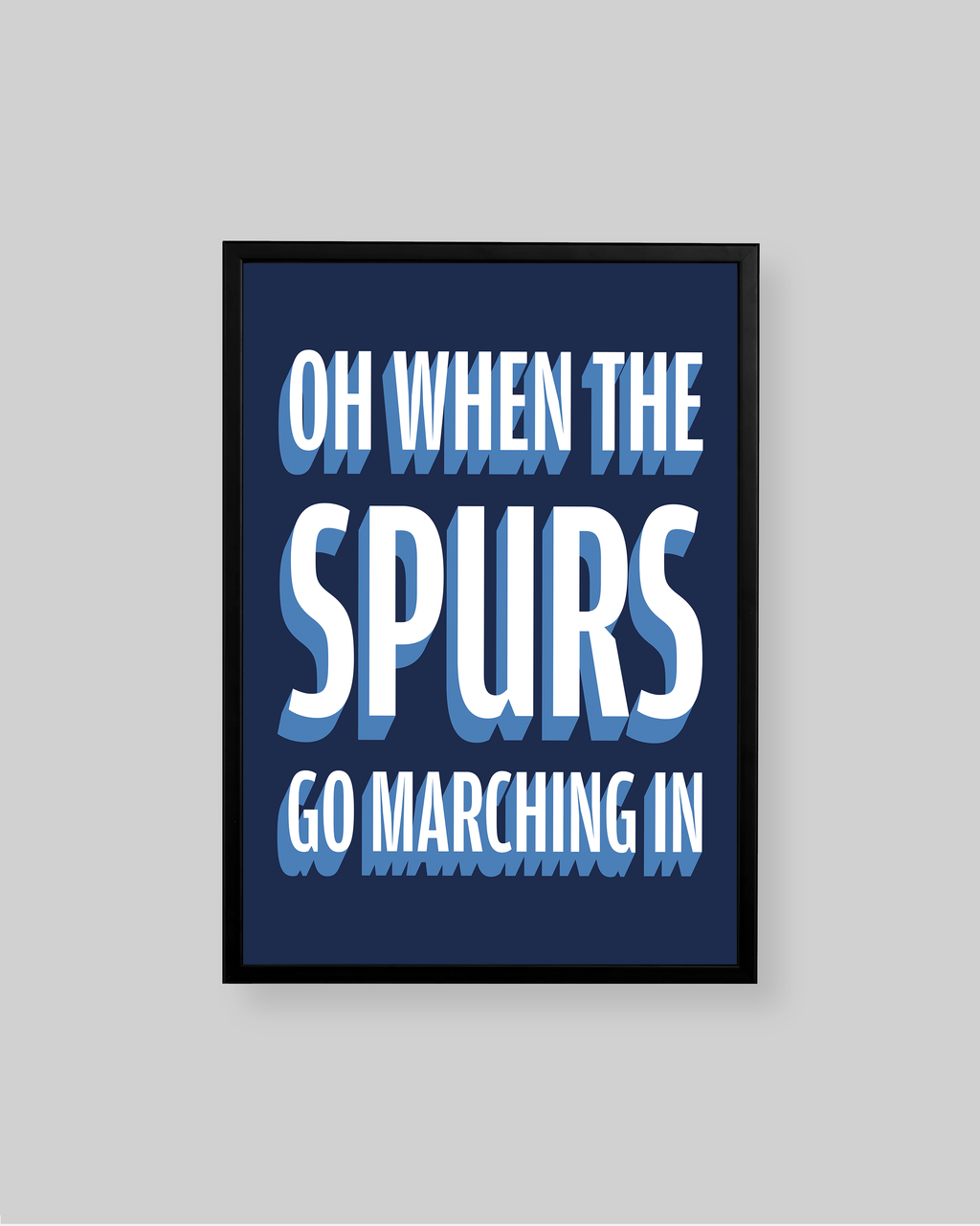 A framed typographic wall art print with the text 'OH WHEN THE SPURS GO MARCHING IN' in white and light blue lettering on a dark navy background, shown against a light gray wall.