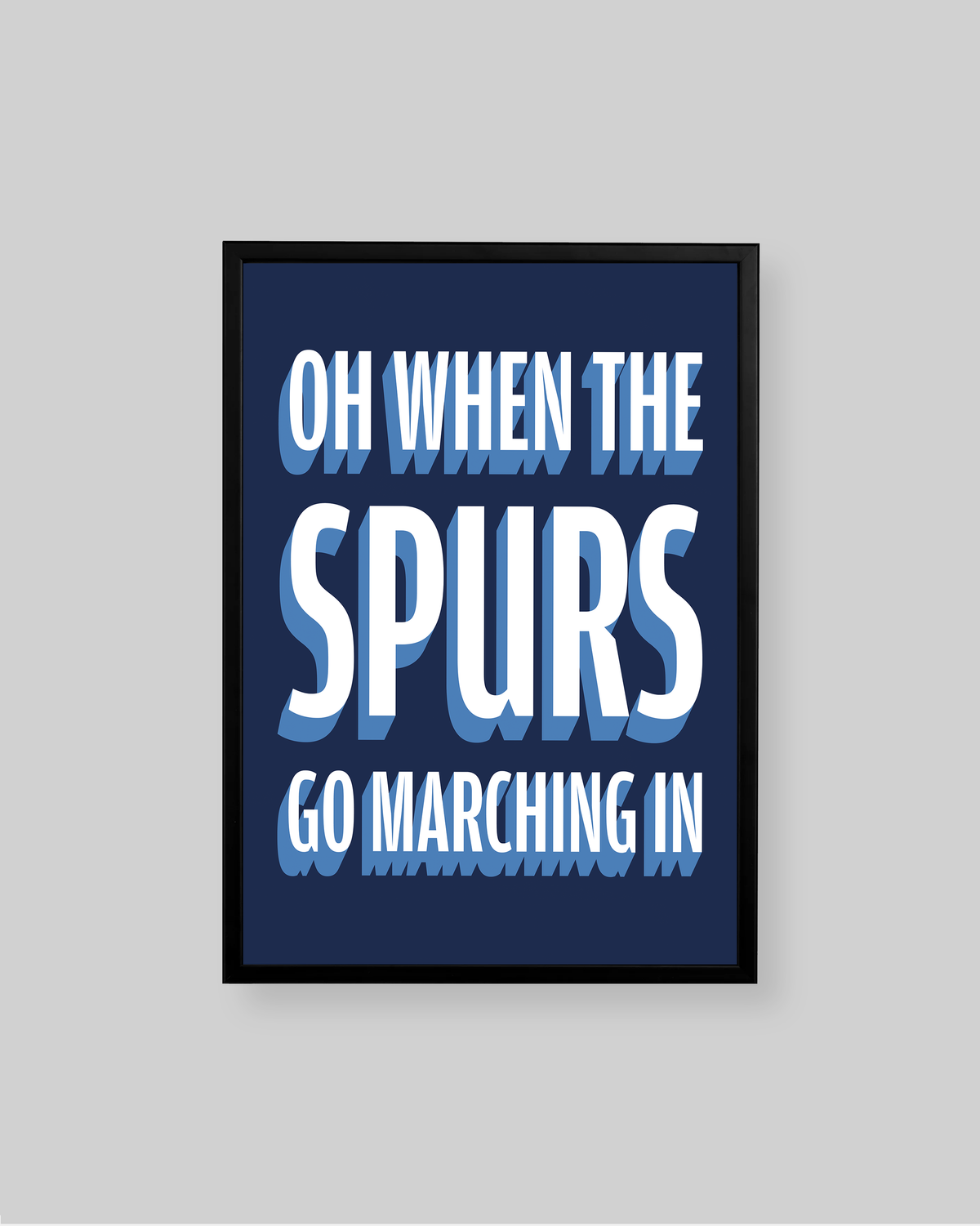 A framed typographic wall art print with the text 'OH WHEN THE SPURS GO MARCHING IN' in white and light blue lettering on a dark navy background, shown against a light gray wall.
